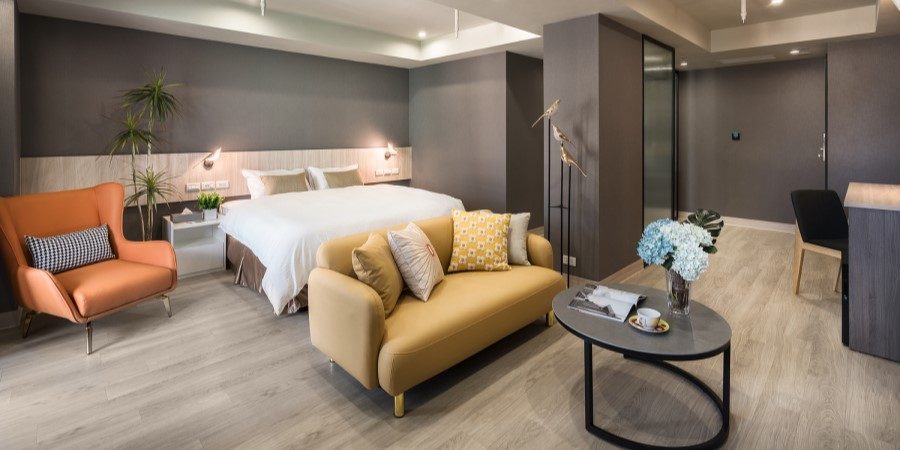 Interior of a hotel room with a cozy bed, a chair, and a table arranged for guests.